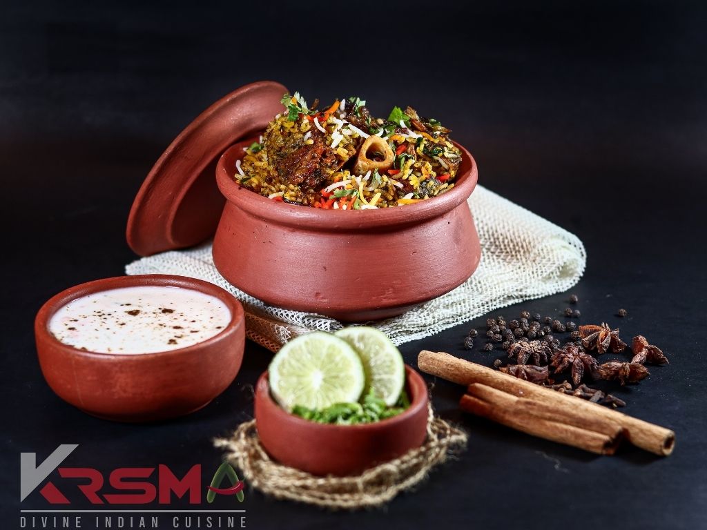 Bone-in biryani in a clay pot with raita and lime at KRSMA Indian Restaurant, Vancouver